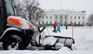 A plow removes snow from the sidewalk in Lafayette Park on Thursday as people make their way past the White House during D.C.&#39;s  worst snowstorm in four years. (associated press)
