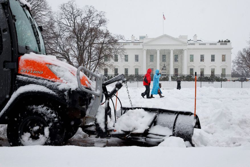 A plow removes snow from the sidewalk in Lafayette Park on Thursday as people make their way past the White House during D.C.'s worst snowstorm in four years. (associated press)