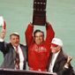 **FILE** Philadelphia Phillies manager Jim Fregosi, center, holds up the NL Championship trophy as Phillies general Manager Lee Thomas, left, and Phillies President Bill Giles look on during their drive around the field after the Phillies 6-3 win over the Atlanta Braves in Game 6 of the NL Playoffs, Oct. 14, 1993, Philadelphia, Pa. (AP Photo/George Widman)