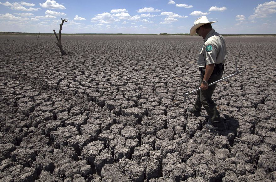 FILE - In this Aug 3, 2011 file photo, Texas State Park police officer Thomas Bigham walks across the cracked lake bed of O.C. Fisher Lake, in San Angelo, Texas. The impacts of record-breaking heat and years of low or no rainfall can be felt years after the dry spell passes, and Texas is now struggling with some of the worst impacts of a historic one-year drought that crippled the state’s lakes, agriculture and water supplies. More than 50 percent of Texas remains in drought despite more consistent rainfall in the past two years, climatologists said. (AP Photo/Tony Gutierrez, File)