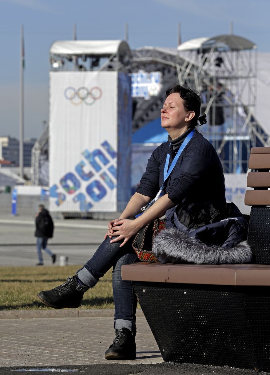 A woman enjoys some warm sunlight in the Olympic Park at the 2014 Winter Olympics, Wednesday, Feb. 12, 2014, in Sochi, Russia. Temperatures are predicted near 60 degrees Fahrenheit in Sochi on Wednesday. (AP Photo/Morry Gash)
