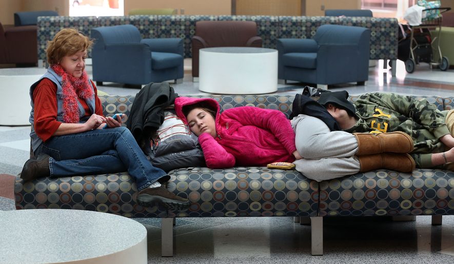 Janie Funai, left, of Mechanicsville, Va., plays "Candy Crush" on her phone while waiting with her children Emma, 16, center, and Ben, 25, for a flight at Richmond International Airport, Thursday. Feb. 13, 2014. They arrived around 5 a.m. with Ben to catch a 6:55 a.m. flight which was canceled. They were waiting to board a flight to Charlotte, N.C. Ben is on his way to Las Vegas to see a performance by Britney Spears. (AP Photo/Richmond Times-Dispatch, P. Kevin Morley)