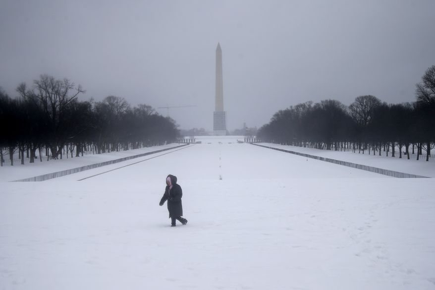 Maria Valero walks in the snow after taking photographs of the reflecting pool and the Washington Monument in Washington, Thursday, Feb. 13, 2014. After pummeling wide swaths of the South, a winter storm dumped nearly a foot of snow in Washington as it marched Northeast and threatened more power outages, traffic headaches and widespread closures for millions of residents. (AP Photo/Charles Dharapak)