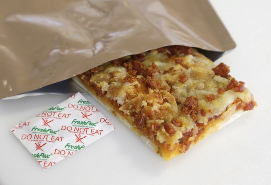 In this Thursday, Feb. 6, 2014 photo, a slice of prototype pizza, in development to be used in MRE's — meals ready to eat, sits in a packet next to a smaller packet known as an oxygen scavenger, left, at the U.S. Army Natick Soldier Research, Development and Engineering Center, Thursday, Feb. 6, 2014, in Natick, Mass. Pizza is in development to be used in individual field rations known as meal ready to eat, or MREs. It has been one of the most requested options for soldiers craving a slice of normalcy in the battlefield and disaster areas. (AP Photo/Steven Senne)
