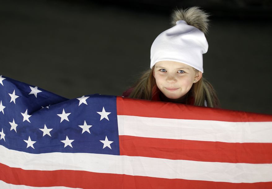 A young fan with an American flag waits for the start of the men's two-man bobsled competition at the 2014 Winter Olympics, Sunday, Feb. 16, 2014, in Krasnaya Polyana, Russia. (AP Photo/Natacha Pisarenko)