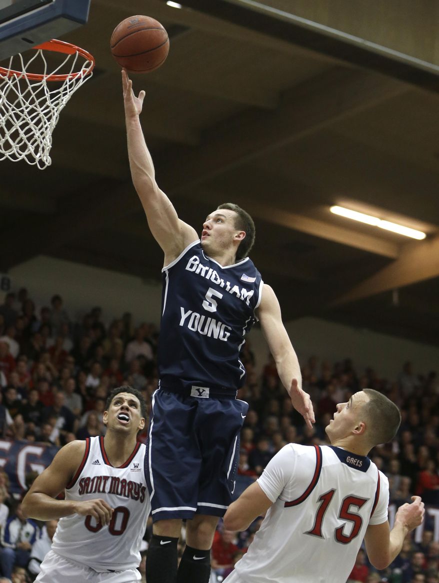 BYU's Kyle Collinsworth (5) lays up a shot between Saint Mary's Brad Waldow, left, and Beau Levesque (15) in the first half of an NCAA college basketball game on Saturday, Feb. 15, 2014, in Moraga, Calif. (AP Photo/Ben Margot)