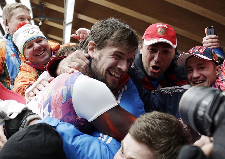 Alexander Tretiakov of Russia celebrates with fans and supporters in the finish area after he won the gold medal during the men's skeleton competition at the 2014 Winter Olympics, Saturday, Feb. 15, 2014, in Krasnaya Polyana, Russia. (AP Photo/Michael Sohn)