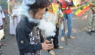 In this Feb. 6, 2013, photo, a Rastafarian named Bongho Jatusy smokes a pipe of marijuana outside a museum dedicated to the memory of late reggae icon Bob Marley in Kingston, Jamaica. (AP Photo/David McFadden, File)