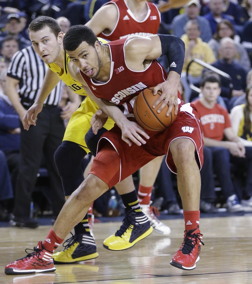 Michigan guard Nik Stauskas, left, reaches in on Wisconsin guard Traevon Jackson (12) during the second half of an NCAA college basketball game in Ann Arbor, Mich., Sunday, Feb. 16, 2014. Wisconsin defeated Michigan 75-62. (AP Photo/Carlos Osorio)