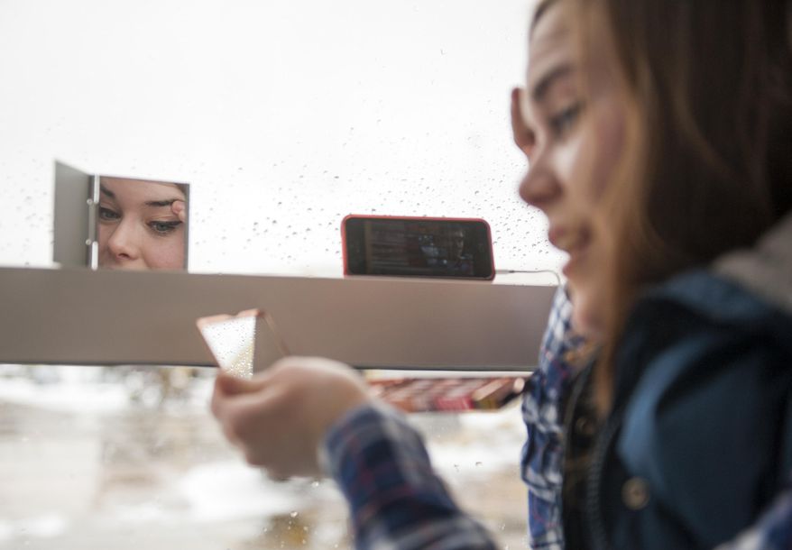 Cara Webster, 24, of Washington, applies makeup as she passes the time while waiting for a flight to Houston, Thursday, Feb. 13, 2014, at Washington's Ronald Reagan National Airport. After pummeling wide swaths of the South, a winter storm dumped nearly a foot of snow in Washington as it marched Northeast and threatened more power outages, traffic headaches and widespread closures for millions of residents. (AP Photo/Cliff Owen)
