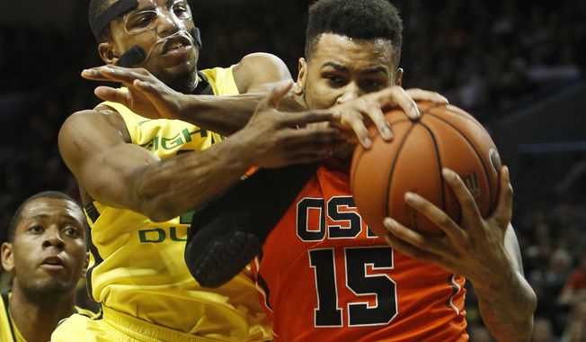 With teammate Mike Moser, left, looking on, Oregon&#x27;s Johnathan Loyd, center, battles Oregon State&#x27;s Eric Moreland for a rebound during the second half an NCAA college basketball game in Eugene, Ore., Sunday, Feb. 16, 2014. (AP Photo/Chris Pietsch)
