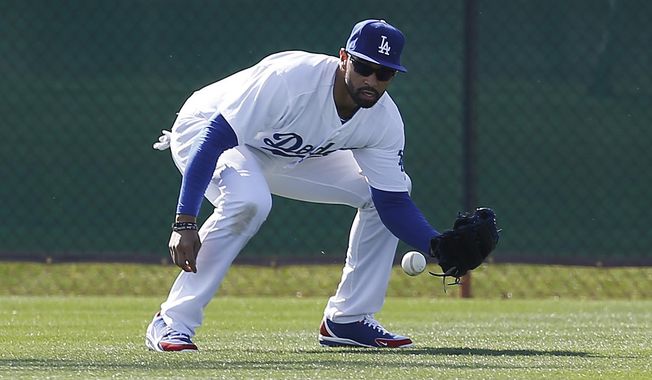 Los Angeles Dodgers center fielder Matt Kemp fields a ball during spring training baseball practice in Glendale, Ariz., Friday, Feb. 14, 2014. (AP Photo/Paul Sancya)