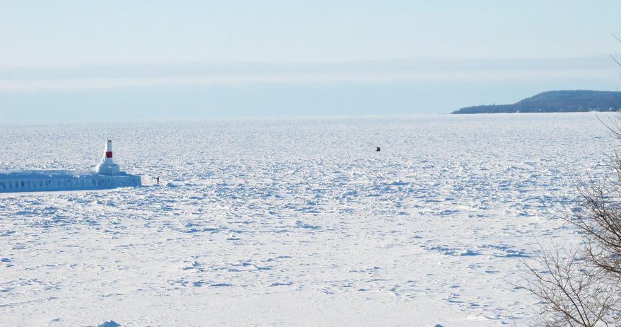 This Feb. 11, 2014 photo the pier and lighthouse at Lake Michigan’s Little Traverse Bay at Petoskey, Mich., is surrounded by thick ice. Nearly 88 percent of the Great Lakes’ surface area has frozen over this winter, the most extensive ice-over in 20 years. (AP Photo/John Flesher)