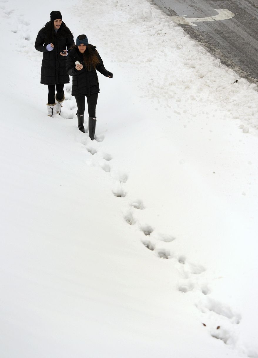 Jackie Lavitt, left, of New York, and Tali Azoolin of Miami, both freshmen at Towson University, follow footprints left in the snow in Towson, Md. on Thursday, Feb. 13, 2014. The storm was the biggest in Maryland in four years, prompting a state of emergency declaration by the governor. (AP Photo/Steve Ruark)