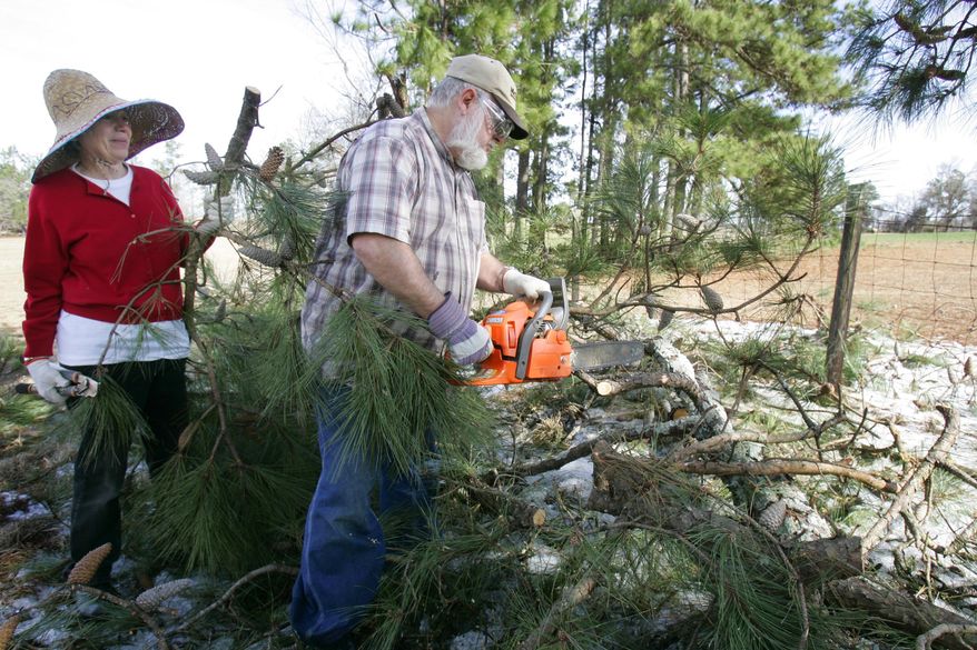 Stan and Tedda Howard work to clear fallen limbs from their pasture fence as they have been without power since this weeks ice storm Friday, Feb. 14, 2014, in Williston, SC. For thousands of South Carolina residents, it will be a long wait to get the power back. About 295,000 customers in the state weathered another night in the dark, and officials warned it could be next week before power is back on for everyone. (AP Photo/Mary Ann Chastain)