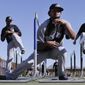 Colorado Rockies pitcher Manuel Corpas, center, ducks under a hurdle in front of teammates LaTroy Hawkins, left, and Greg Burke, right, during spring training baseball practice, Monday, Feb. 17, 2014, in Scottsdale, Ariz.  (AP Photo/Gregory Bull)