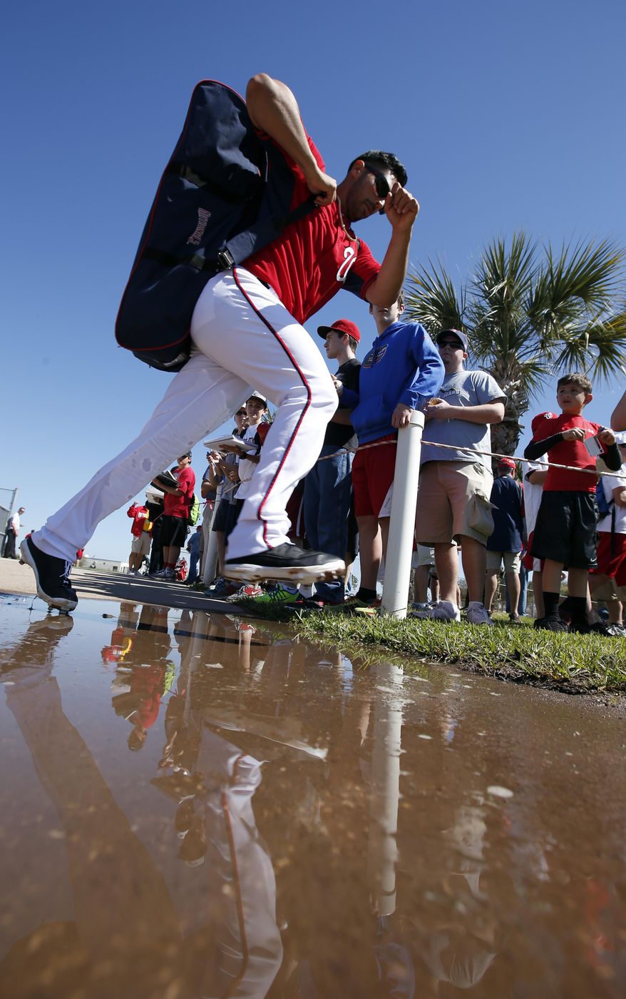 Washington Nationals starting pitcher Gio Gonzalez hops a puddle after signing autographs following a spring training baseball workout, Monday, Feb. 17, 2014, in Viera, Fla. (AP Photo/Alex Brandon)