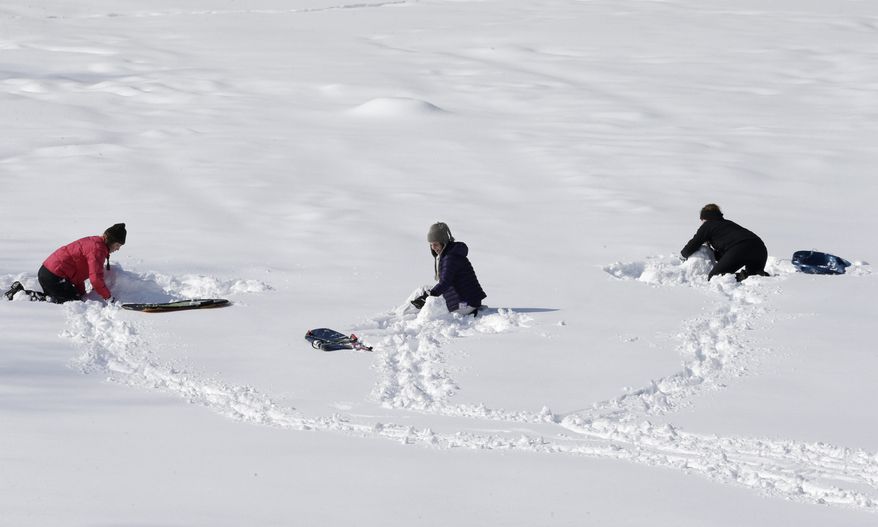 Three people take a break from sledding and make snow sculptures at the Cleveland MetroParks South Chagrin Reservation Tuesday, Feb. 18, 2014, in Solon, Ohio. This has been one of Ohio's coldest, snowiest winters in years. All that snow and ice has left some local governments short on road salt. Many schools have used up their allotted snow days and may have to make up classes.(AP Photo/Tony Dejak)