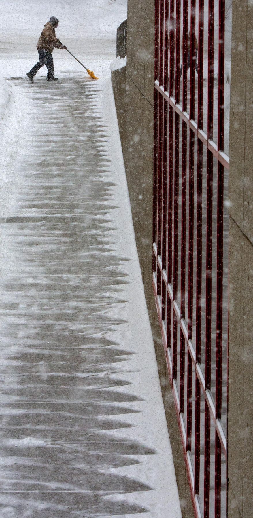 O.B. Gladyness works to shovel a sidewalk along Lyon Street NE, near the Grand Rapids Community College Student Center, in downtown Grand Rapids Monday, Feb. 17, 2014. "It can go away any day," he said. Gladyness works for the college's facilities department. (AP Photo/The Grand Rapids Press, Cory Morse)