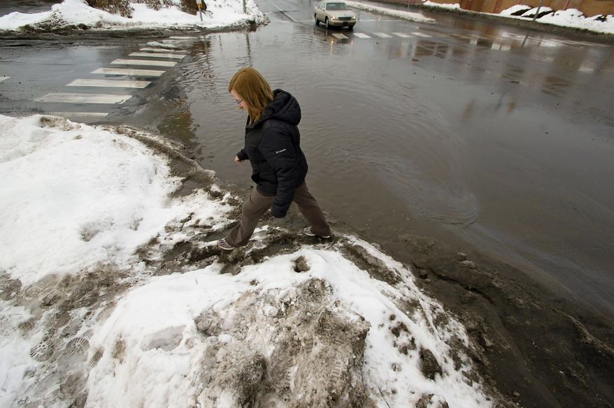 A pedestrian carefully walks in a mess of melting snow next to the flooded intersection of Franklin Avenue and Mulberry Street on a mild Wednesday, Feb. 19, 2014, in downtown Scranton, Pa. Weeks of subfreezing weather are giving way, at least briefly, to temperatures in the 40sd and 50s, putting many Midwestern and Northeastern cities on guard for flooding, roof collapses and clogged storm drains.(AP Photo / The Scranton Times-Tribune, Butch Comegys) WILKES BARRE TIMES-LEADER OUT; MANDATORY CREDIT