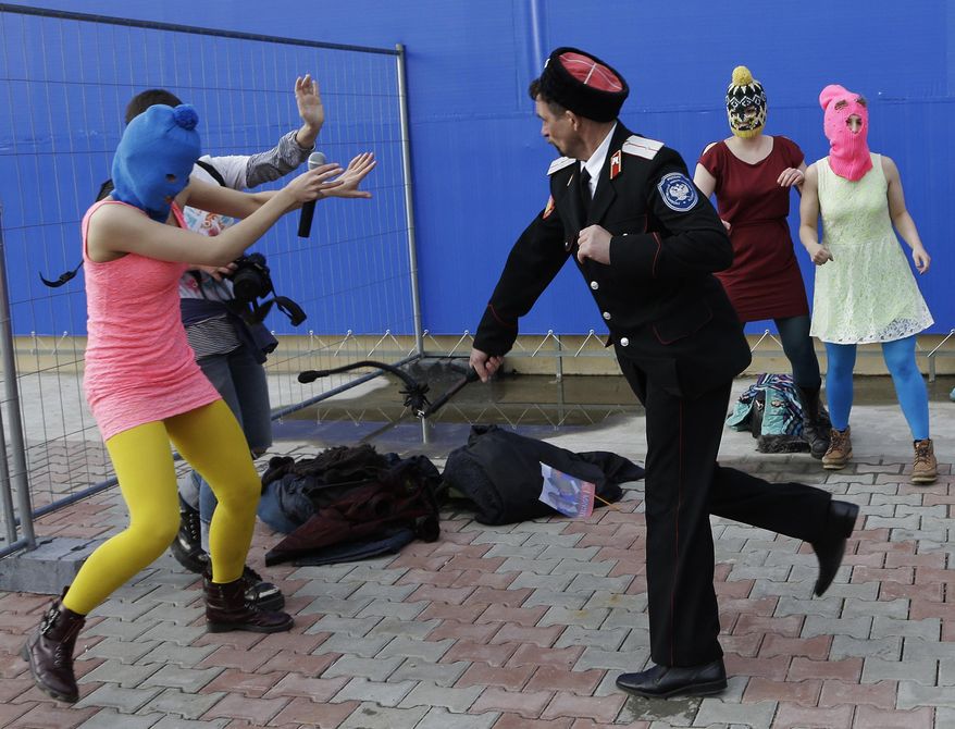 A Cossack militiaman attacks Nadezhda Tolokonnikova and a photographer as she and fellow members of the punk group Pussy Riot, including Maria Alekhina, right, in the pink balaclava, stage a protest performance in Sochi, Russia, on Wednesday, Feb. 19, 2014. The group had gathered in a downtown Sochi restaurant, about 30km (21miles) from where the Winter Olympics are being held. They ran out of the restaurant wearing brightly colored clothes and ski masks and were set upon by about a dozen Cossacks, who are used by police authorities in Russia to patrol the streets. (AP Photo/Morry Gash)