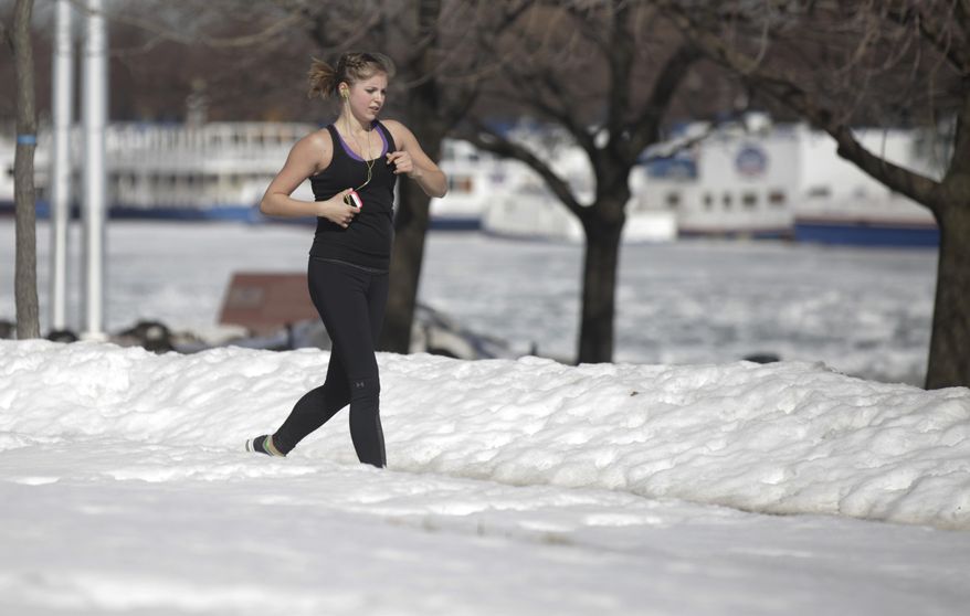 A runner runs along the lake shore Wednesday, Feb. 19, 2014, in Chicago. Weeks of subfreezing weather are giving way, at least briefly, to temperatures in the 50s, putting cities on guard for flooding, roof collapses and clogged storm drains. (AP Photo/Kiichiro Sato)