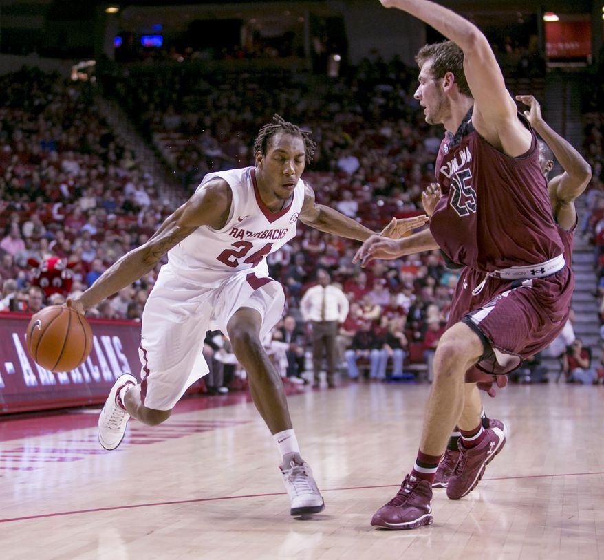 Arkansas guard Michael Qualls (24) fakes to the basket against  South Carolina forward Mindaugas Kacinas (25) during the first half of an NCAA college basketball game, Wednesday, Feb. 19, 2014, in Fayetteville, Ark. (AP Photo/Gareth Patterson)