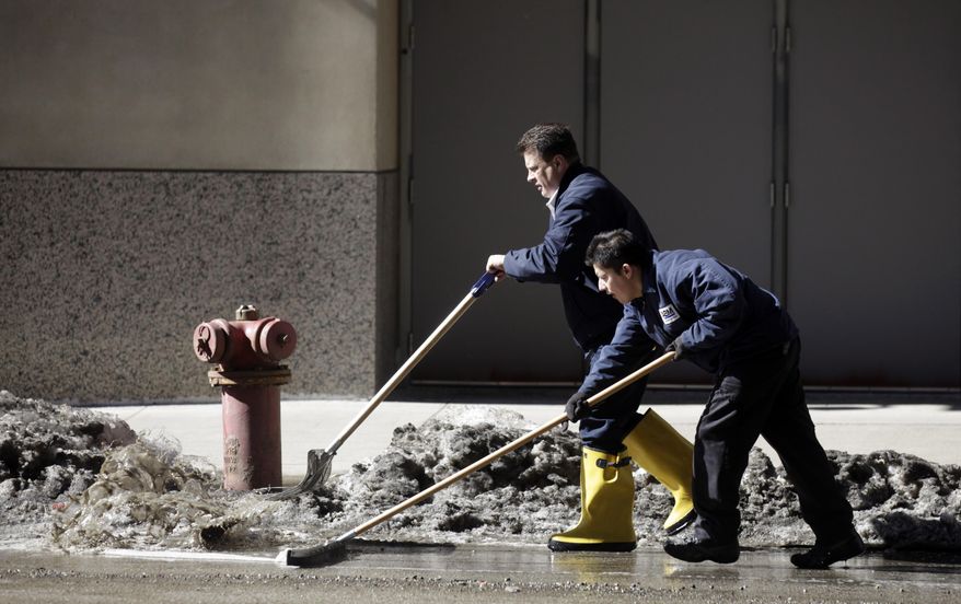 Workers at a downtown parking garage removes snow melt water to the storm drain Wednesday, Feb. 19, 2014, in Chicago. Weeks of subfreezing weather are giving way, at least briefly, to temperatures in the 50s, putting cities on guard for flooding, roof collapses and clogged storm drains. (AP Photo/Kiichiro Sato)