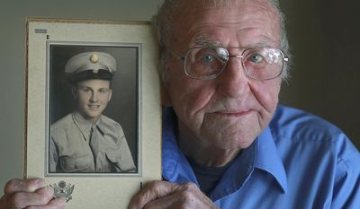 ADVANCE FOR USE SATURDAY, FEB. 22 AND THEREAFTER - In this Jan. 31, 2014, 2014 photo, World War II veteran Lynold Puterbaugh holds a portrait of him in his Army uniform that was taken in 1944 at his home in Pleasant Hill, Ill. (AP Photo/The Quincy Herald-Whig, Phil Carlson)
