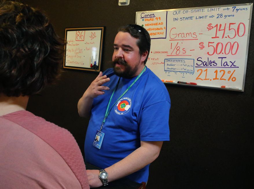 FILE - In this Feb. 14, 2014, file photo, pot store employee Sam Walsh informs a first time customer about different strains of marijuana, a white board listing prices and sales tax, inside the retail shop at 3D Cannabis Center, in Denver. Colorado Gov. John Hickenlooper announced on Feb. 19, 2014 a plan to start spending nearly $100 million in marijuana tax money, the first signal of how much Colorado is reaping from recreational pot sales and what it plans to spend the money on. (AP Photo/Brennan Linsley)