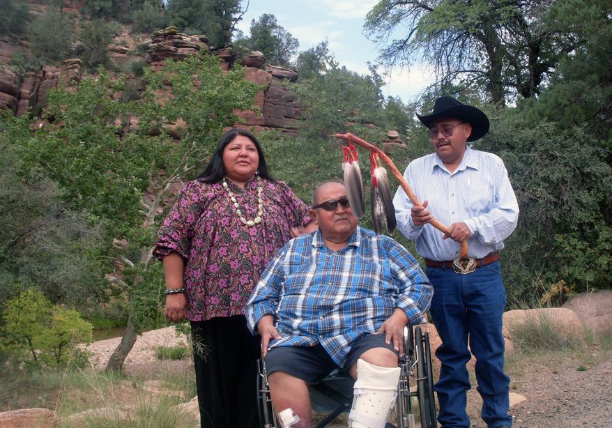This 2013 photo released courtesy of the San Carlos Apache Tribe shows Vernelda Grant, director of the Historic Preservation and Archaeology Department for the San Carlos Apache Tribe, left, with Vincent Randall, cultural director for the Yavapai-Apache Nation, center, and Wally Davis Jr., vice chairman of the Tonto Apache Tribe, gathered near the Verde River in central Arizona. Two dozen tribal ceremonial items purchased last year at auction in France are set to return to Arizona. A U.S. charitable foundation paid $530,000 for the hoods and ornate masks to give them to the Hopi and two Apache tribes, which use them to invoke the ancestral spirits in ceremonies. (AP Photo/Twila Cassadore, San Carlos Apache Tribe)