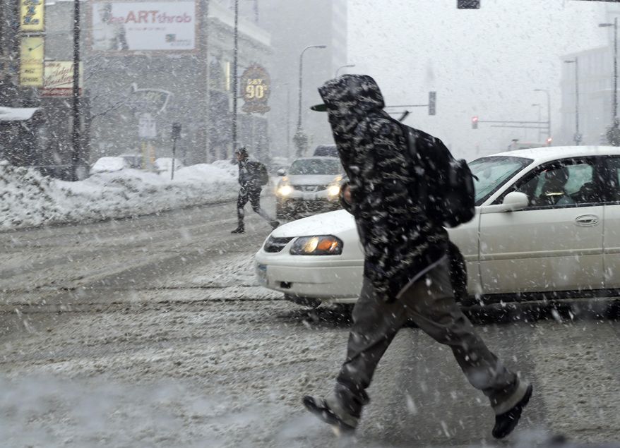 A pedestrian makes a hasty crossing on a downtown Minneapolis street Thursday, Feb. 20, 2014 as blowing and heavy wet snow from a new winter storm hit eastern Minnesota and western Wisconsin. (AP Photo/Jim Mone)