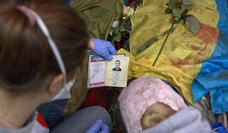 A paramedic looks at the identification document of a killed anti-government protester, in central Kiev, Ukraine, Thursday, Feb. 20, 2014. A brief truce in Ukraine&#39;s embattled capital failed Thursday, spiraling into fierce clashes between police and anti-government protesters. (AP Photo/Darko Bandic)