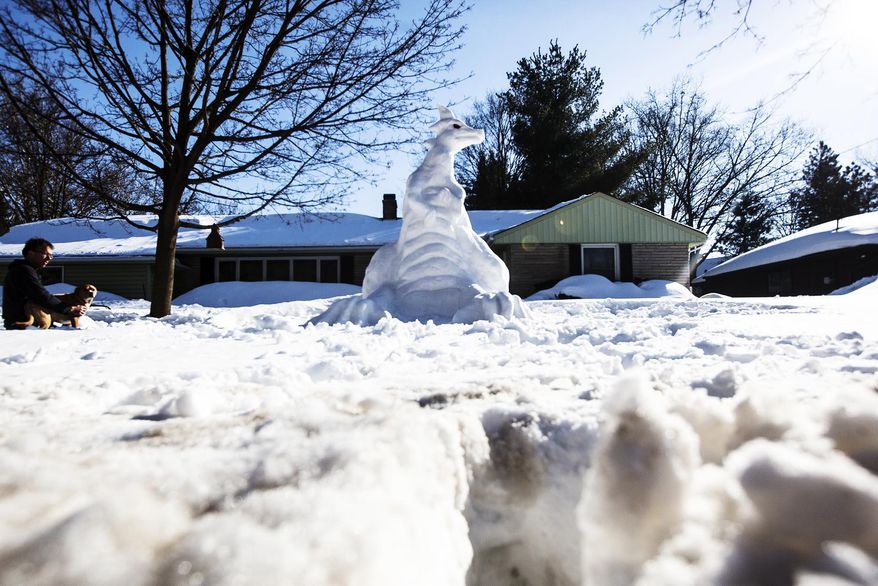 Mike Huver sits off to the side looking on at his recently completed snow dragon on Thursday, Feb. 20, 2014 in Kalamazoo, Mich. Huver sways it took him five hours to build the snowdragon. (AP Photo/Kalamazoo Gazette-MLive Media Group, Chuck Miller ) ALL LOCAL TV OUT; LOCAL TV INTERNET OUT
