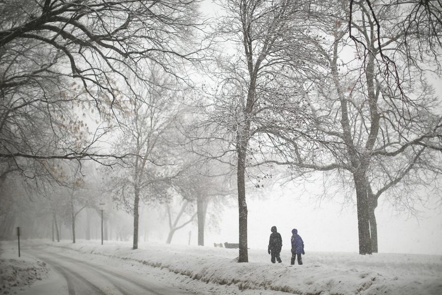 What forecasters say might be the largest snowfall of the winter began falling Thursday, Feb. 20, 2014 in Minneapolis. Two women walked around Lake Harriet Thursday afternoon in the snow. (AP Photo/The Star Tribune, Jeff Wheeler)