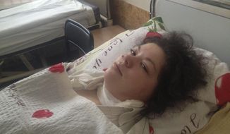 Olesya Zhukovska lies on her hospital bed in Kiev, Ukraine, Friday, Feb. 21, 2014. “I am dying,” Olesya Zhukovska, a 21-year-old volunteer medic wrote on Twitter, minutes after she got hit in the neck by a sniper bullet as deadly clashes broke out in the center of the Ukrainian capital between protesters and police. But miraculously, Zhukovska survived, becoming a symbol of the three month-long protest against President Viktor Yanukvoych’s government. (AP Photo/Maria Danilova)