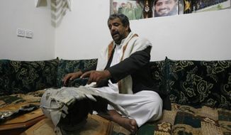 In this photo taken on Tuesday, Feb. 11, 2014, Himyar al-Qadhy, whose brother Adnan, was  killed in 2012 by U.S drone strike east of Sanaa, Yemen, points to what he says is the rocket that killed his brother, a Yemeni army brigadier suspected of involvement in a militant attack in 2008 against the US Embassy in Sanaa. The brother denies that Adnan was a member of the al-Qaida. The portrait on the wall shows his late brother. (AP Photo/Hani Mohammed)