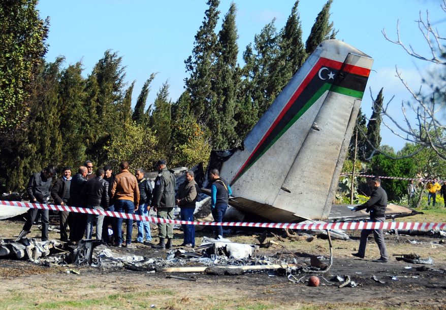 Tunisian investigators examine the site of a Libyan Antonov 26 aircraft that crashed near the village of Benyanou at 40 kilometers (25 miles) southeast of Tunis, the capital, Friday, Feb. 21, 2014. A medical flight from Libya crashed in a field near Tunis in the early hours of Friday morning, killing all 11 Libyans on board, Tunisia's civil defense said. (AP Photo/Hassene Dridi)