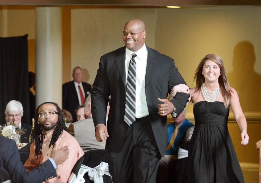 Georgia Sports Hall of Fame inductee Frank Thomas is escorted to his table during the induction ceremony Saturday night, Feb. 22, 2014, in Macon, Ga. (AP Photo/The Telegraph, Jason Vorhees)