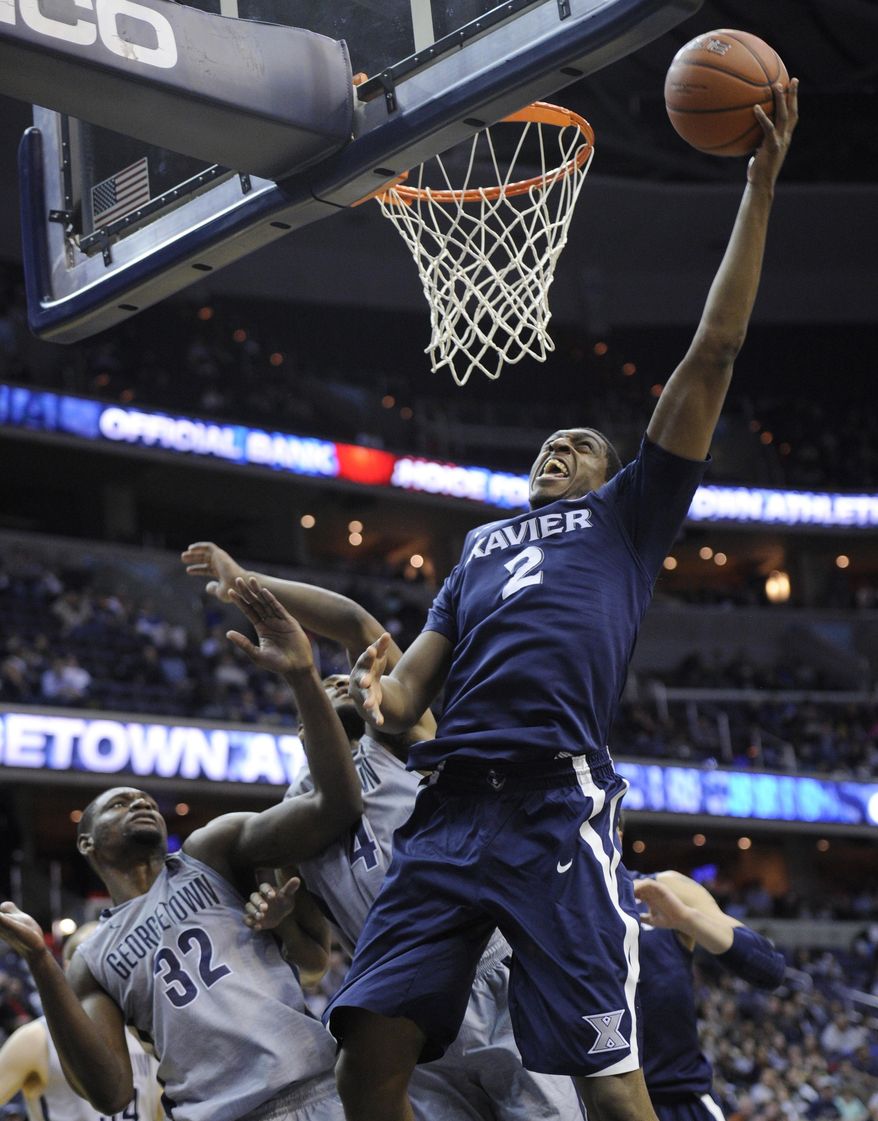 Xavier forward James Farr (2) goes to the basket against Georgetown center Moses Ayegba (32) and D'Vauntes Smith-Rivera (4) during the first half of an NCAA college basketball game, Saturday, Feb. 22, 2014, in Washington. (AP Photo/Nick Wass)