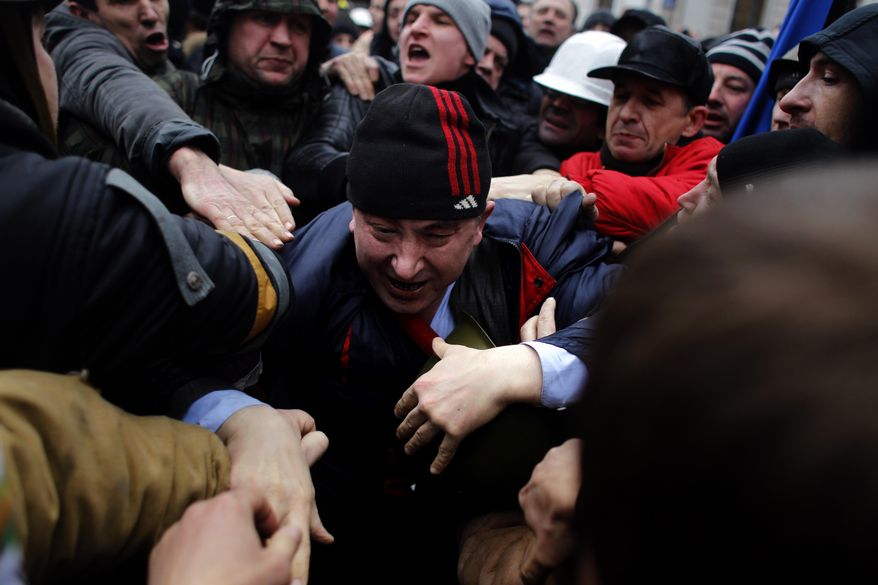 A suspected supporter of Ukraine&#x27;s embattled president Viktor Yanukovych, center, is assaulted by anti-government protesters in Kiev, Ukraine, Saturday, Feb. 22, 2014. Fears that Ukraine could split in two mounted Saturday as regional lawmakers in the pro-Russian east questioned the authority of the national parliament. Protesters took control of Ukraine&#x27;s capital and parliament sought to oust the president. (AP Photo/ Marko Drobnjakovic)
