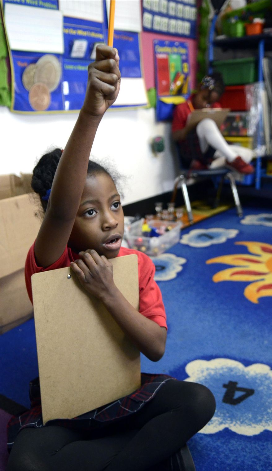 In this photo from Feb 6, 2014, kindergarten student Tomiaya Harrison raises her hand when she completes an assignment at the Chattanooga Charter School for Excellence at the Eastgate Town Center in Chattanooga, Tenn. (AP Photo/Chattanooga Times Free Press, John Rawlston) THE DAILY CITIZEN OUT; NOOGA.COM OUT; CLEVELAND DAILY BANNER OUT; LOCAL INTERNET OUT.