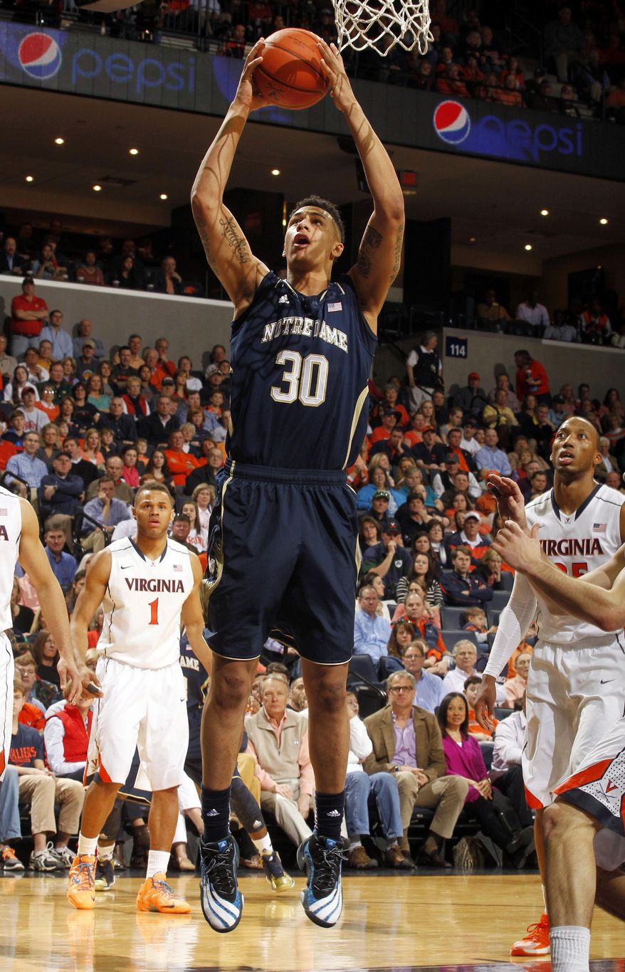 Notre Dame forward Zach Auguste (30) shoots between Virginia defenders during an NCAA college basketball game Saturday, Feb. 22, 2014, in Charlottesville, Va. (AP Photo/Andrew Shurtleff)