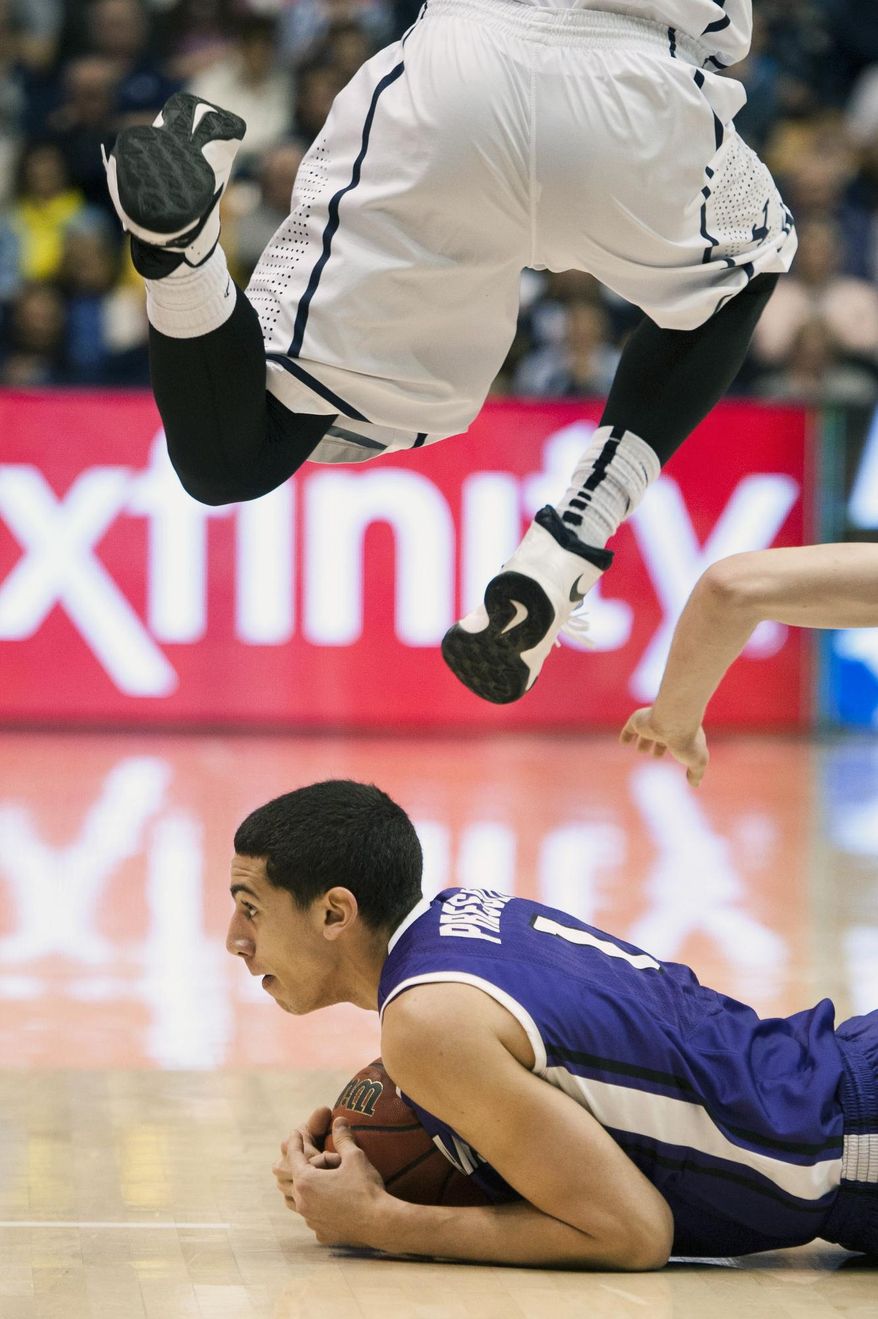 Portland's Bryce Pressley holds on to a loose ball as BYU's Kyle Collinsworth leaps over him during the first half of an NCAA college basketball game in Provo, Utah, Saturday, Feb. 22, 2014. (AP Photo/The Daily Herald, Grant Hindsley)