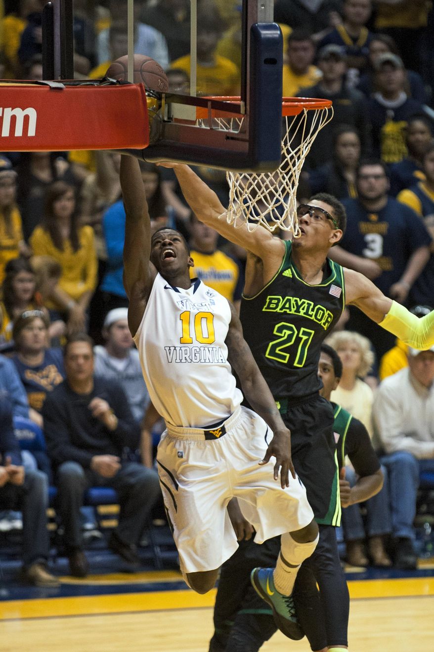 West Virginia's Eron Harris, left, lays in a basket as Baylor's Isaiah Austin defends during the first half of an NCAA college basketball game Saturday, Feb. 22, 2014, in Morgantown, W.Va. (AP Photo/Andrew Ferguson)