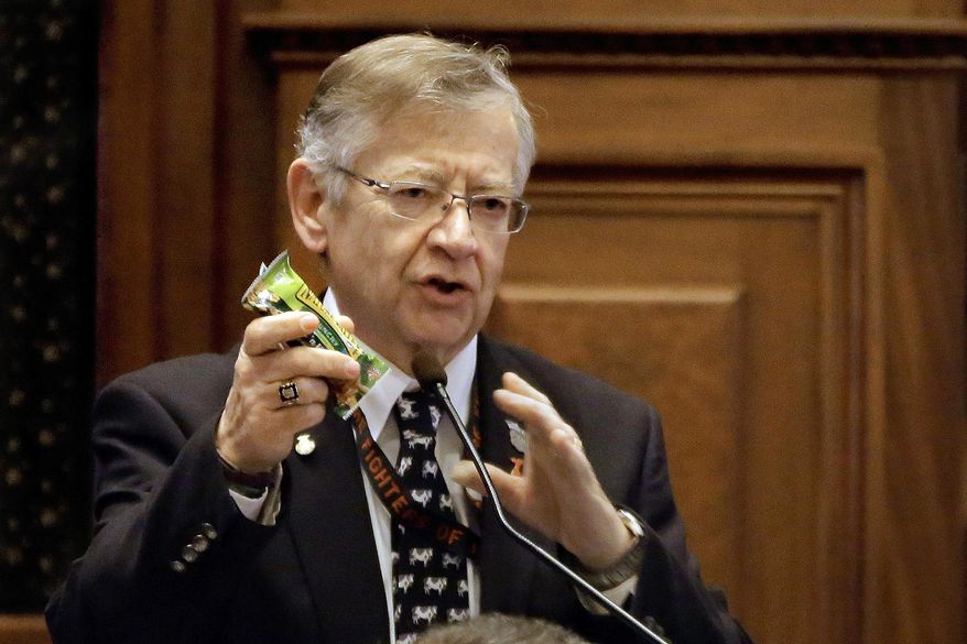 In this Feb. 20, 2014 photo, Illinois state Rep. Donald Moffitt, R-Galesburg, holds up an example of a healthy snack on the House floor encouraging fellow lawmakers, lobbyists or anyone else who wants to shed some pounds and eat healthier to sign up for the "fitness caucus" at the state Capitol in Springfield, Ill. The caucus will kick off with a weight-loss competition and run through this year's legislative session. Moffitt began an exercise routine two years ago when his doctor said he'd need to lose 10 pounds or take diabetes medication. Since then, he lost 100 pounds and walks five miles a day. (AP Photo/Seth Perlman)