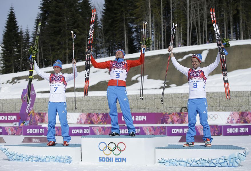 Russia's gold medal winner Alexander Legkov is flanked by Russia's silver medal winner Maxim Vylegzhanin, left and Russia's bronze medal winner Ilia Chernousov during the flower ceremony of the men's 50K cross-country race at the 2014 Winter Olympics, Sunday, Feb. 23, 2014, in Krasnaya Polyana, Russia. (AP Photo/Gregorio Borgia)
