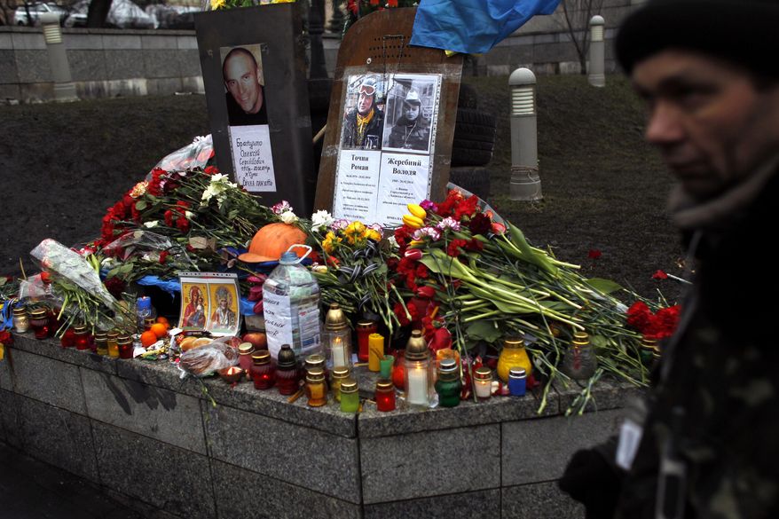A man passes by a small memorial dedicated to people killed in clashes with the police at Independence Square in Kiev, Ukraine, Sunday, Feb. 23, 2014. The Kiev protest camp at the center of the anti-President Viktor Yanukovych movement filled with more and more dedicated demonstrators Sunday morning setting up new tents after a day that saw a stunning reversal of fortune in a political standoff that has left scores dead and worried the United States, Europe and Russia. (AP Photo/ Marko Drobnjakovic)