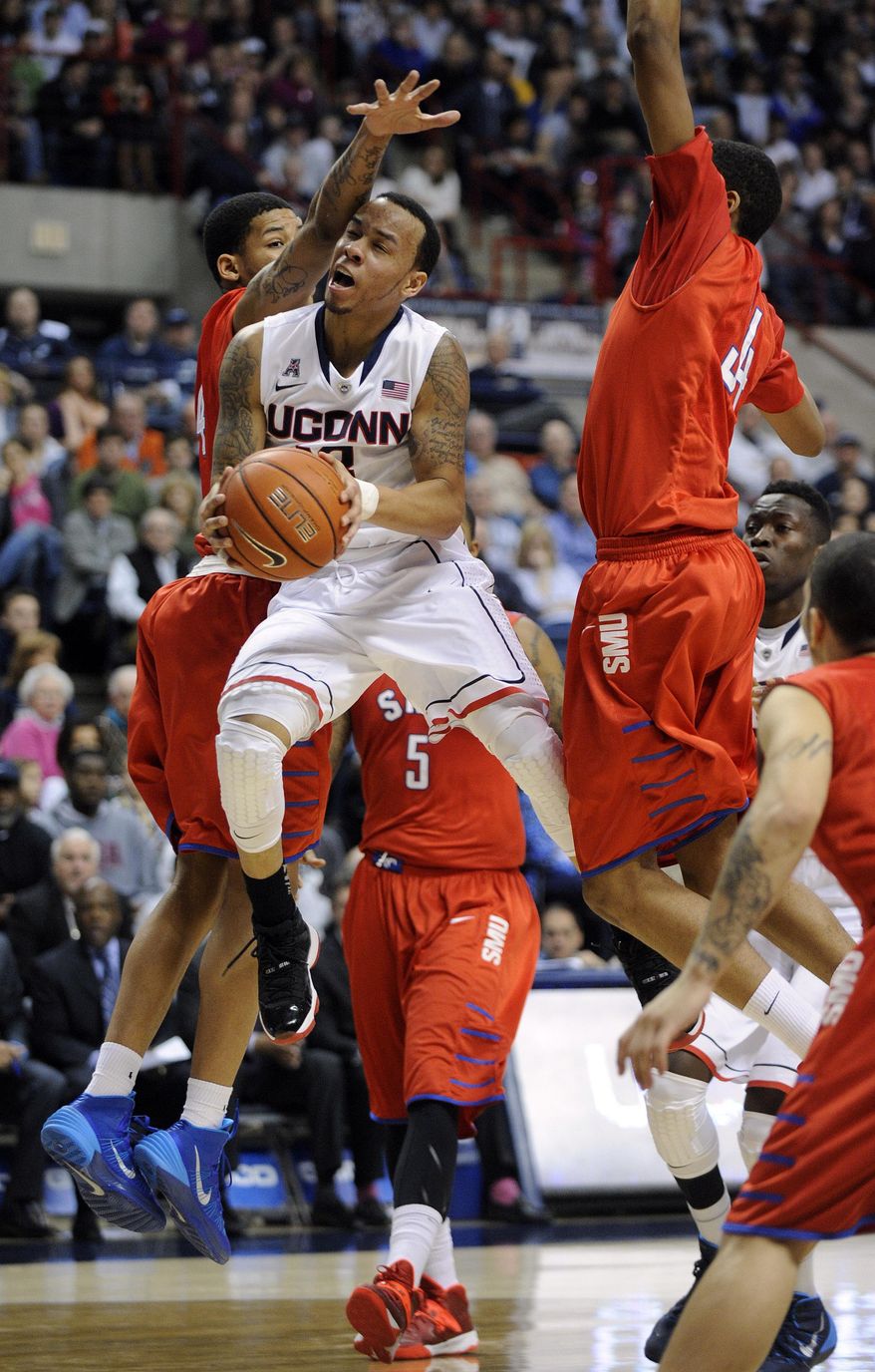 Connecticut's Shabazz Napier (13) is guarded by SMU's Keith Frazier, left, and Ben Moore (34) during the second half of SMU's 64-55 victory in an NCAA college basketball game in Storrs, Conn., Sunday, Feb. 23, 2014. (AP Photo/Fred Beckham)