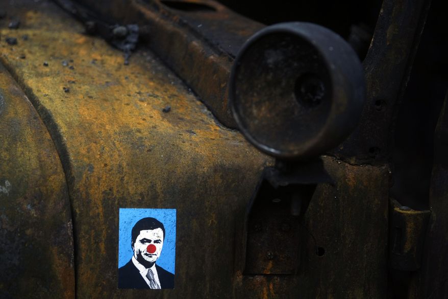 A sticker depicting Ukrainian President Viktor Yanukovych is placed on a burned military truck in Kiev, Ukraine, Sunday, Feb. 23, 2014. The Kiev protest camp at the center of the anti-President Viktor Yanukovych movement filled with more and more dedicated demonstrators Sunday morning setting up new tents after a day that saw a stunning reversal of fortune in a political standoff that has left scores dead and worried the United States, Europe and Russia. (AP Photo/ Marko Drobnjakovic)